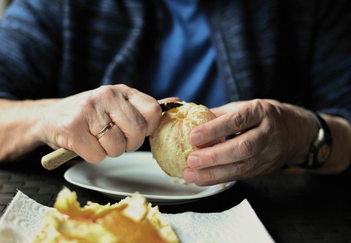 older adult peeling orange