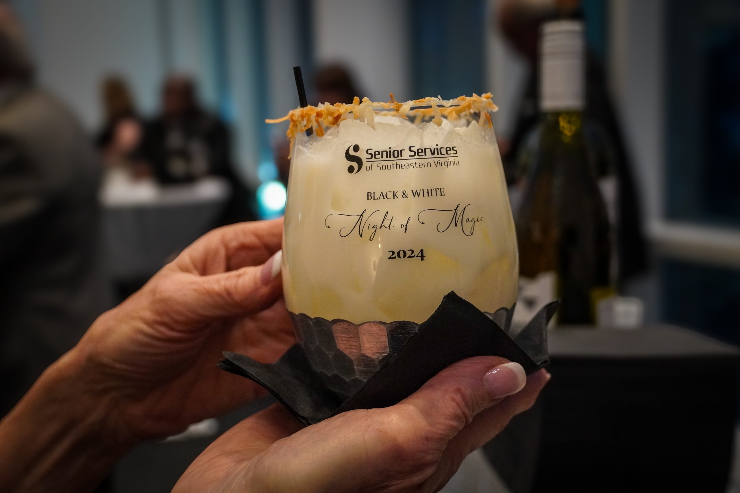 signature cocktail in senior services commemorative glass being held by woman
