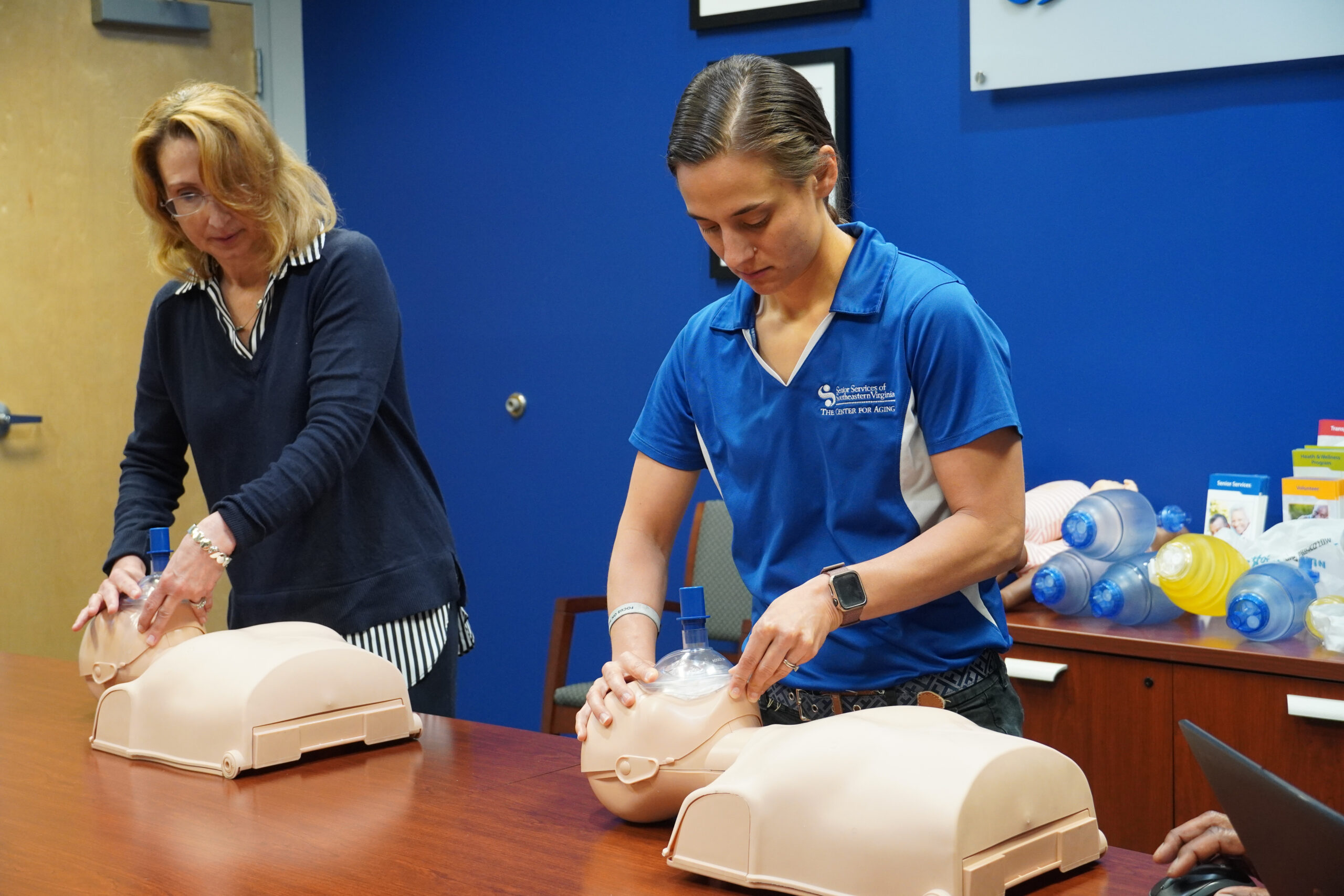 Two female adults handling cpr dummies
