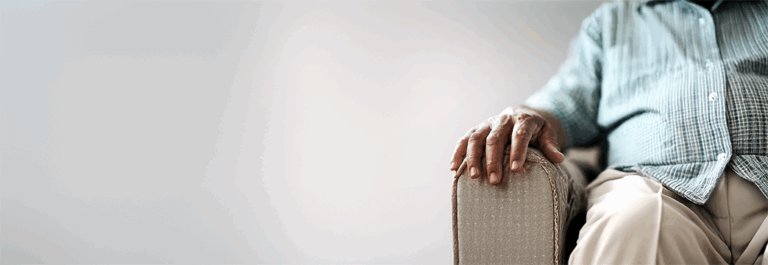 Older man seated in old couch chair.