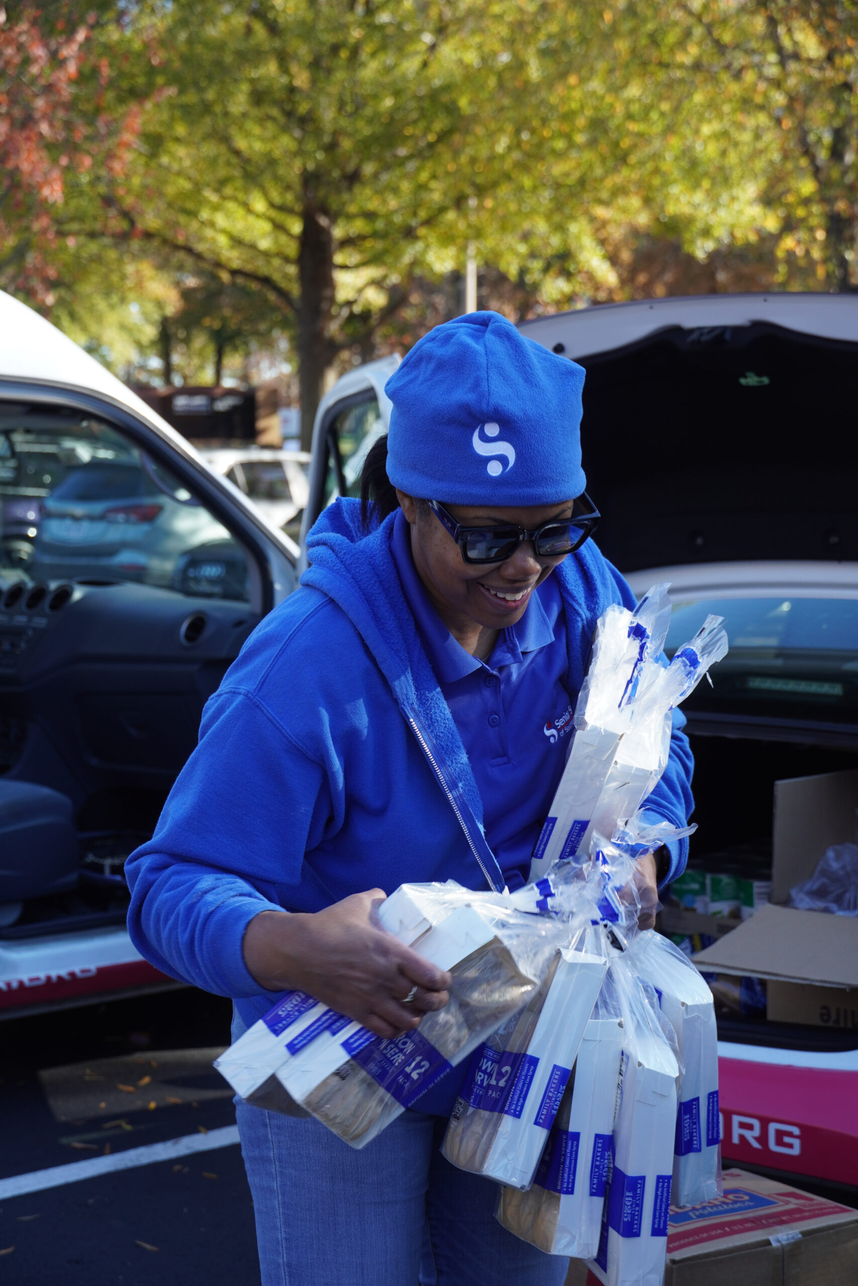 woman in blue hoodie holding bags of rolls