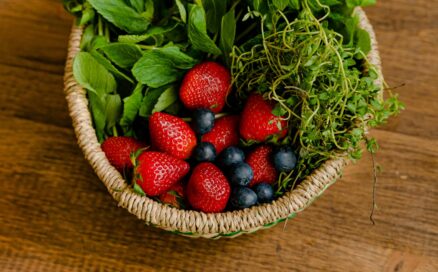 A basket of herbs, sprouts, strawberries, and blueberries