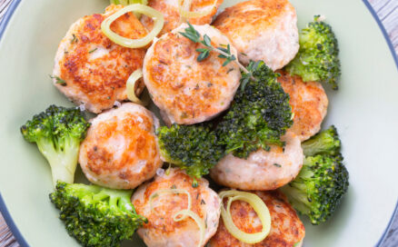 Plate of salmon meatballs with vegetables on a wooden table