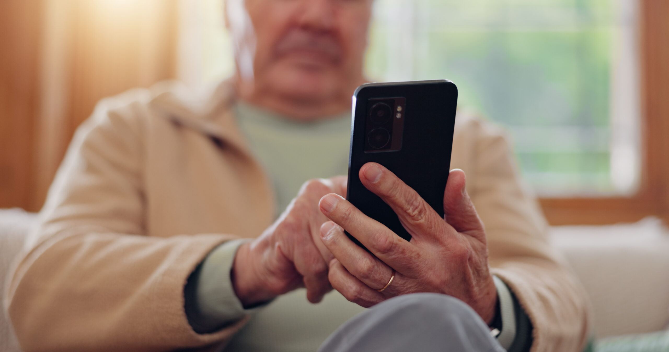 old man sitting, typing on cellphone